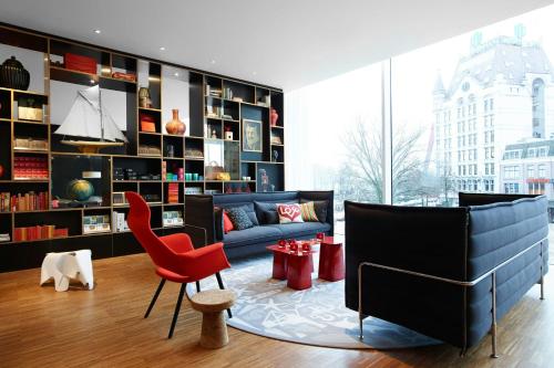 a living room with a blue couch and a red chair at citizenM Rotterdam in Rotterdam