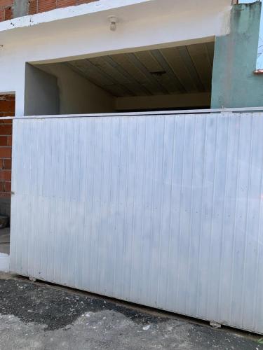 ein weißes Garagentor aus Metall mit einer Wand in der Unterkunft Casa para temporada- Pq Mambucaba in Angra dos Reis