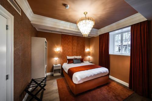 une chambre avec un grand lit et un lustre dans l'établissement Hotel Kasteel Oost, à Fauquemont