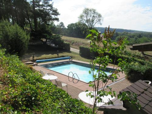 - une piscine avec des tables et des chaises dans la cour dans l'établissement Ferienhäuser Mit Pool In Ruhiger Lage Am Waldrand, à Niederaula