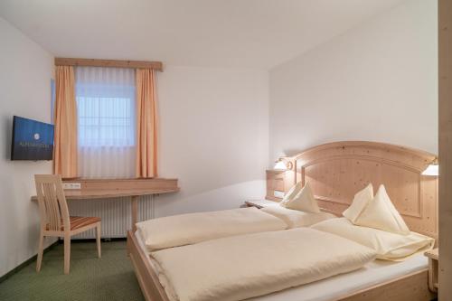 a bedroom with a bed and a desk and a chair at Alpenresidenz am Mühlbach in Obergurgl