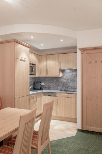 a kitchen with wooden cabinets and a wooden table and chairs at Alpenresidenz am Mühlbach in Obergurgl