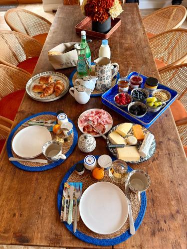 een houten tafel met borden met eten erop bij Le Patio Bleu in Saint-Romain