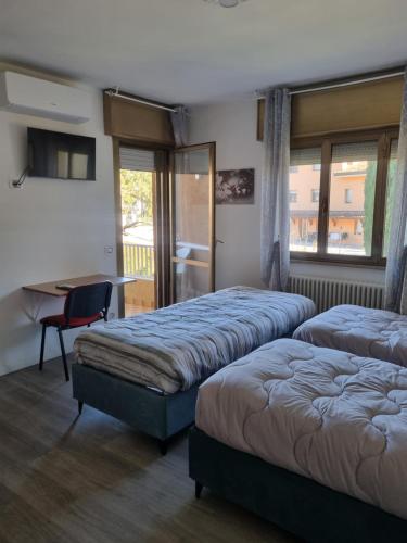 2 camas en una habitación con mesa y escritorio en Affittacamere Ely, en San Giorgio di Nogaro