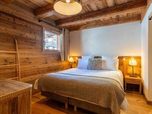 ein Schlafzimmer mit einem Bett in einem Zimmer mit Holzwänden in der Unterkunft Demi-chalet moderne 4 chambres + dortoir, terrasse, garage - La Clusaz - FR-1-459-238 in La Clusaz