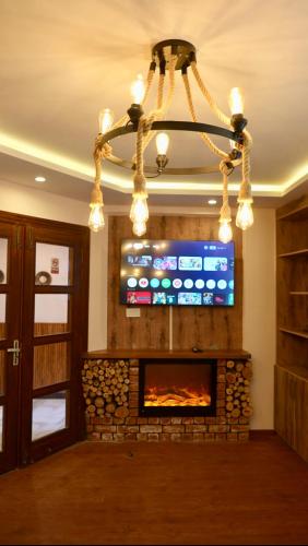 a fireplace in a living room with a television and a chandelier at Ortus - Murree Hills in Murree