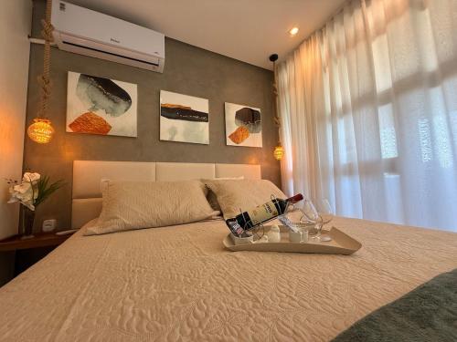 a bed with a tray of wine bottles and glasses on it at Conforto Frente ao Mar - Areia Preta in Guarapari