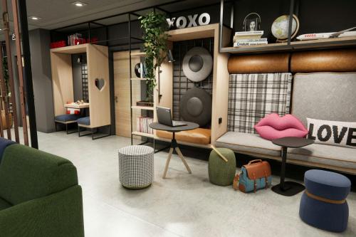 een kamer met een bank, stoelen en een laptop bij Moxy Zurich in Zürich