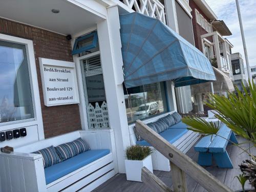 a porch with blue benches and an umbrella at Bed&Breakfast aan Strand in Katwijk aan Zee