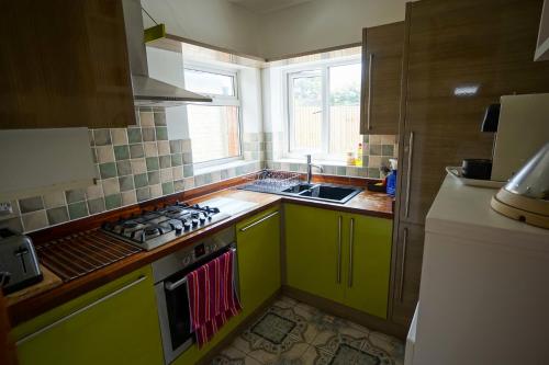 a kitchen with green cabinets and a stove top oven at Charming 2 BDR Home with Garden and Light in London