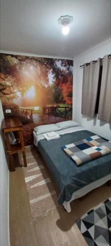 ein Schlafzimmer mit einem Bett und einem Gemälde an der Wand in der Unterkunft Casa Container em Monte Verde - 800m do Centro in Monte Verde
