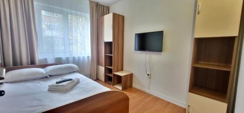 a bedroom with a bed with a television on the wall at Homzy Craiova in Craiova