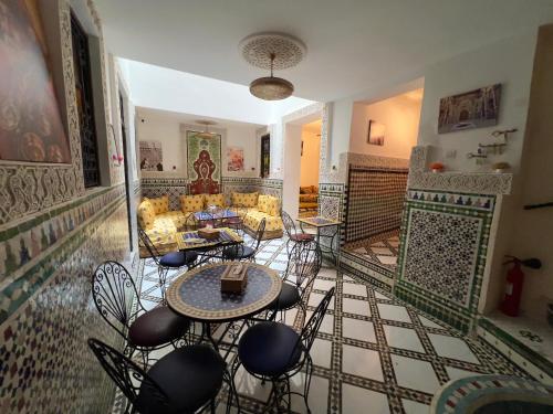una sala de estar con sofá, mesas y sillas en Riad Dar Sbil, en Fez