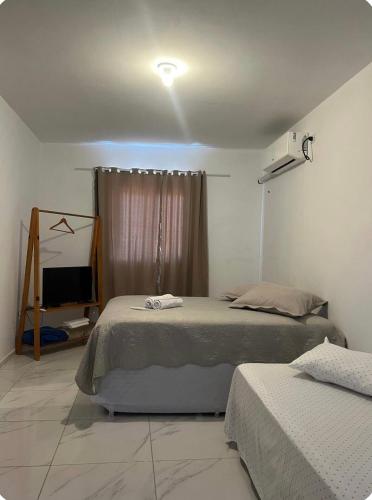 a bedroom with two beds and a television in it at Apartamento da Kenia in Canoa Quebrada