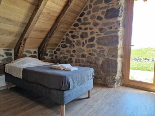 a bed in a room with a stone wall at Buron de Léon, en plein cœur de l Aubrac in Laguiole