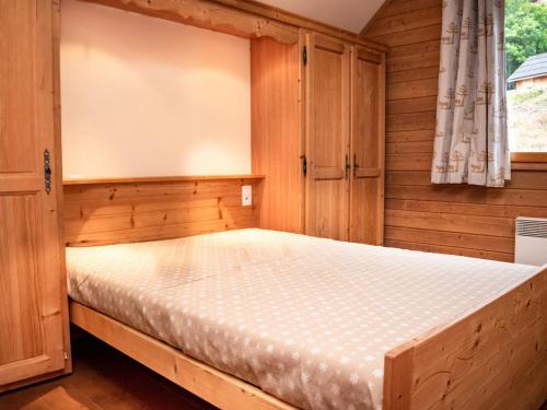 ein Schlafzimmer mit einem Bett in einem Holzzimmer in der Unterkunft Charmant Chalet 6 Pers. avec Terrasse et Parking - Résidence Les Chalets de Praroustan, Pra Loup 1500 - FR-1-504-364 in Uvernet