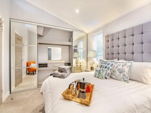 a bedroom with a large white bed with a basket on it at Sandbanks 2 bed Lodge with hot tub - L1 in Brynteg