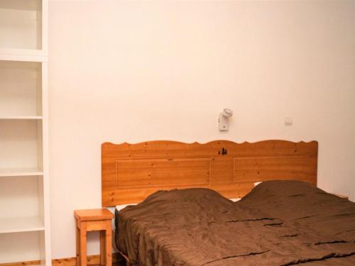 un lit avec une tête de lit en bois dans une chambre dans l'établissement 2 Pièces PMR avec Balcon & Cuisine Équipée à Superdevoluy - FR-1-504-522, à Superdevoluy