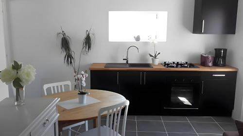 une cuisine avec une table, un évier et une cuisinière dans l'établissement Gite Les Jardins d'Harmonie, à Bourgneuf