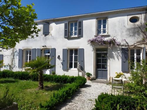 une maison blanche avec des volets bleus et un jardin dans l'établissement Gite La Maison d'Harmonie, à Bourgneuf