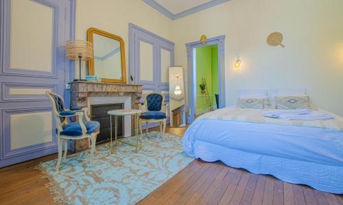 a bedroom with a bed and two chairs and a fireplace at L'instant champenois in Bréviandes