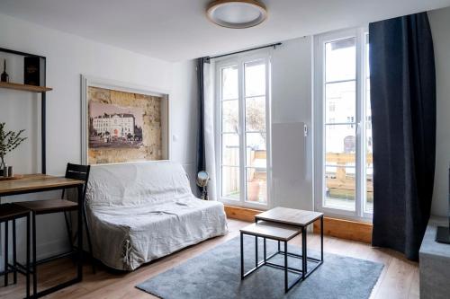 ein Schlafzimmer mit einem Bett, einem Schreibtisch und Fenstern in der Unterkunft Le charme de la place Saint-Sauveur in Caen