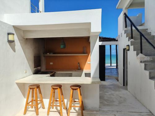 une cuisine avec deux tabourets à côté d'un comptoir dans l'établissement Beach Villa Seaside Sunset Haven Nature & Chill, à Chuburná