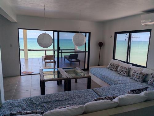 un salon avec un canapé et une table en verre dans l'établissement Beach Villa Seaside Sunset Haven Nature & Chill, à Chuburná
