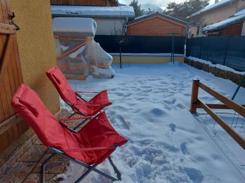 une chaise rouge assise dans la neige dans l'établissement Chalet 126 m² PRALOUP, à Uvernet