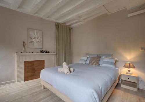 a bedroom with a large white bed and a fireplace at Cozy T2 - Quartier de Nantilly - Saumur in Saumur