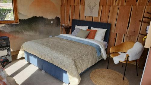 a bedroom with a bed and a chair at Auberge Les Enguenelles Lodges in Châtelblanc