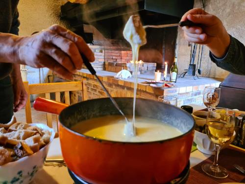 a person stirring a pot of soup with a spoon at Auberge Les Enguenelles Lodges in Châtelblanc