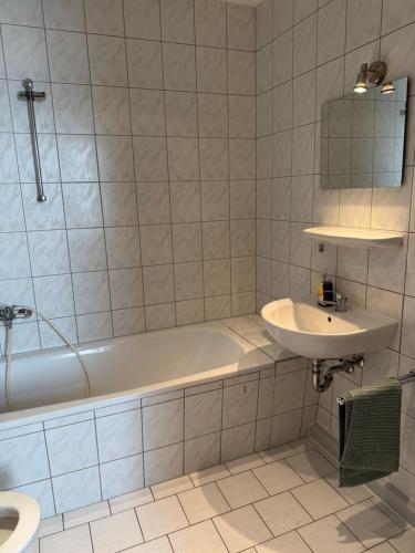 un bagno bianco con vasca e lavandino di Gemütliche Praktische Wohnungen a Gera