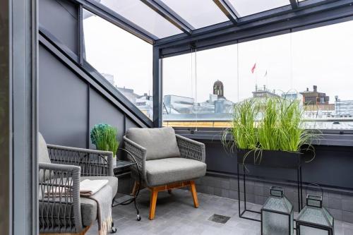 ein Balkon mit Stühlen, Pflanzen und Fenstern in der Unterkunft Scandi City Loft, Jacuzzi, Balcony, AirCon in Helsinki