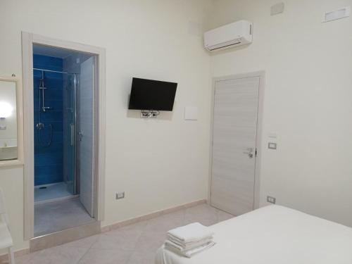 ein weißes Schlafzimmer mit einem Bett und einem TV an der Wand in der Unterkunft Aparthotel Napoli Railway in Neapel