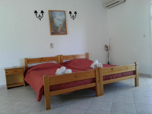 a bedroom with a large wooden bed with red sheets at Elpida Studio in Trapezaki