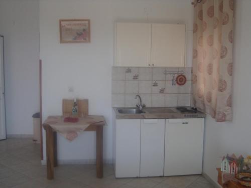 a kitchen with white cabinets and a sink and a table at Elpida Studio in Trapezaki