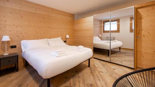 Un dormitorio con una gran cama blanca y un espejo. en Italianway - Trento 2, en Bormio
