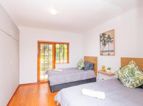 a bedroom with two beds and a window at Prima Rosa Langebaan - seaviews in Langebaan