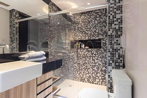 uma casa de banho com um lavatório e um chuveiro com azulejos pretos em Apartamento no coração do Pacaembu em São Paulo