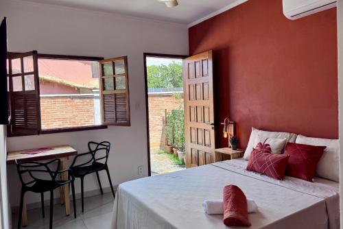 Un dormitorio con una cama y una mesa y una ventana. en Estúdios Sol e Mar, aconchego e charme em Tucuns, en Búzios