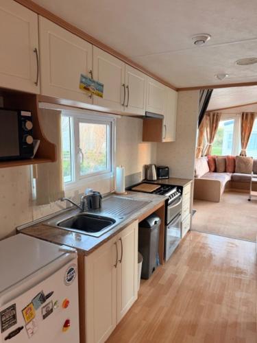 a small kitchen with a sink and a stove at Caravan Wendy 2 Bed Adapted Caravan in Meliden