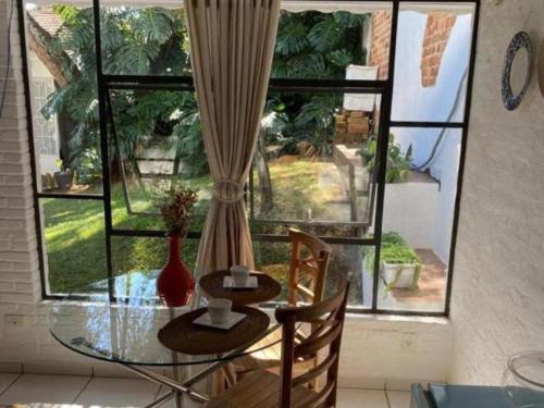 a glass table and chairs in front of a window at Casa Prana in Bragança Paulista