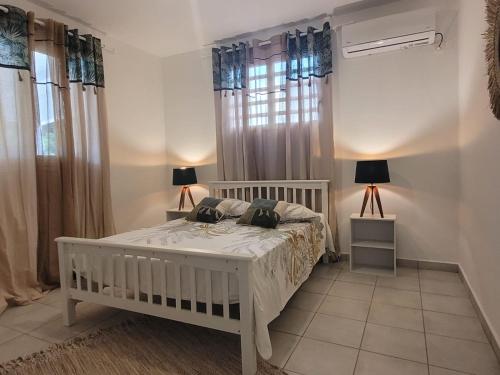 a bedroom with a white bed and a window at Villa Mahault in Petit-Bourg