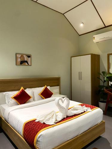 a bedroom with a bed with white sheets and red pillows at Skyleaf Resort in Meenangadi