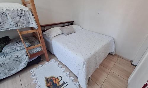 ein kleines Schlafzimmer mit einem Bett und einem Etagenbett in der Unterkunft KITNET S2 em TORRES-RS - Na mais bela praia Gaúcha - Cozinha - Banheiro - Ar condicionado - TV smart 32' - Wi-Fi - Estacionamento - Anfitriã Superhost no BnB in Torres