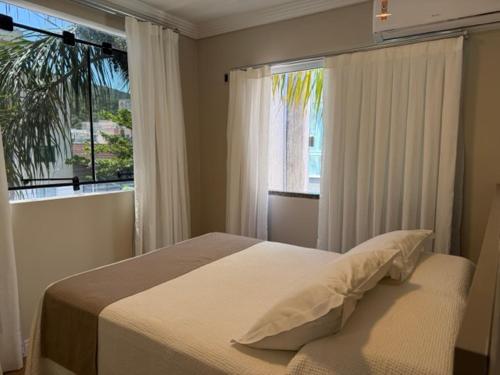 a bedroom with a bed and a large window at Pousada Cristalmar in Bombinhas