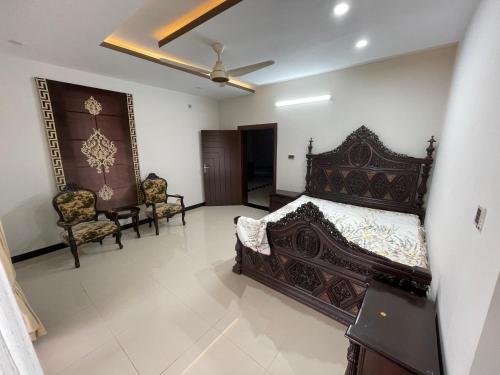 a bedroom with a large bed and two chairs at Ranim Family Lodge Abbottabad in Abbottābād