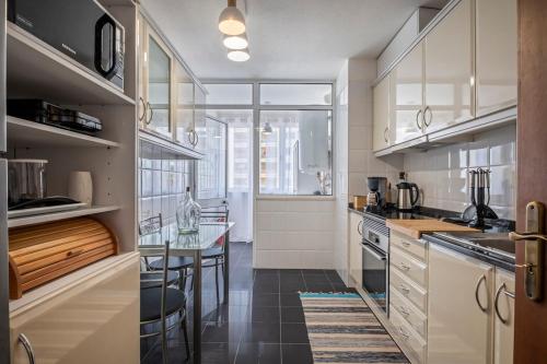 a kitchen with white cabinets and a glass table at Nata7 Apartment in Funchal