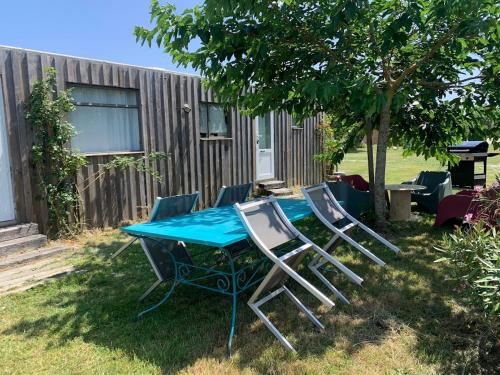 une table de pique-nique et quatre chaises dans une cour dans l'établissement Mobil Home Vintage à la Ferme des buttons, à Rosnay